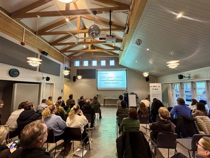 en gruppe mennesker som sitter i et rom og ser på en skjerm