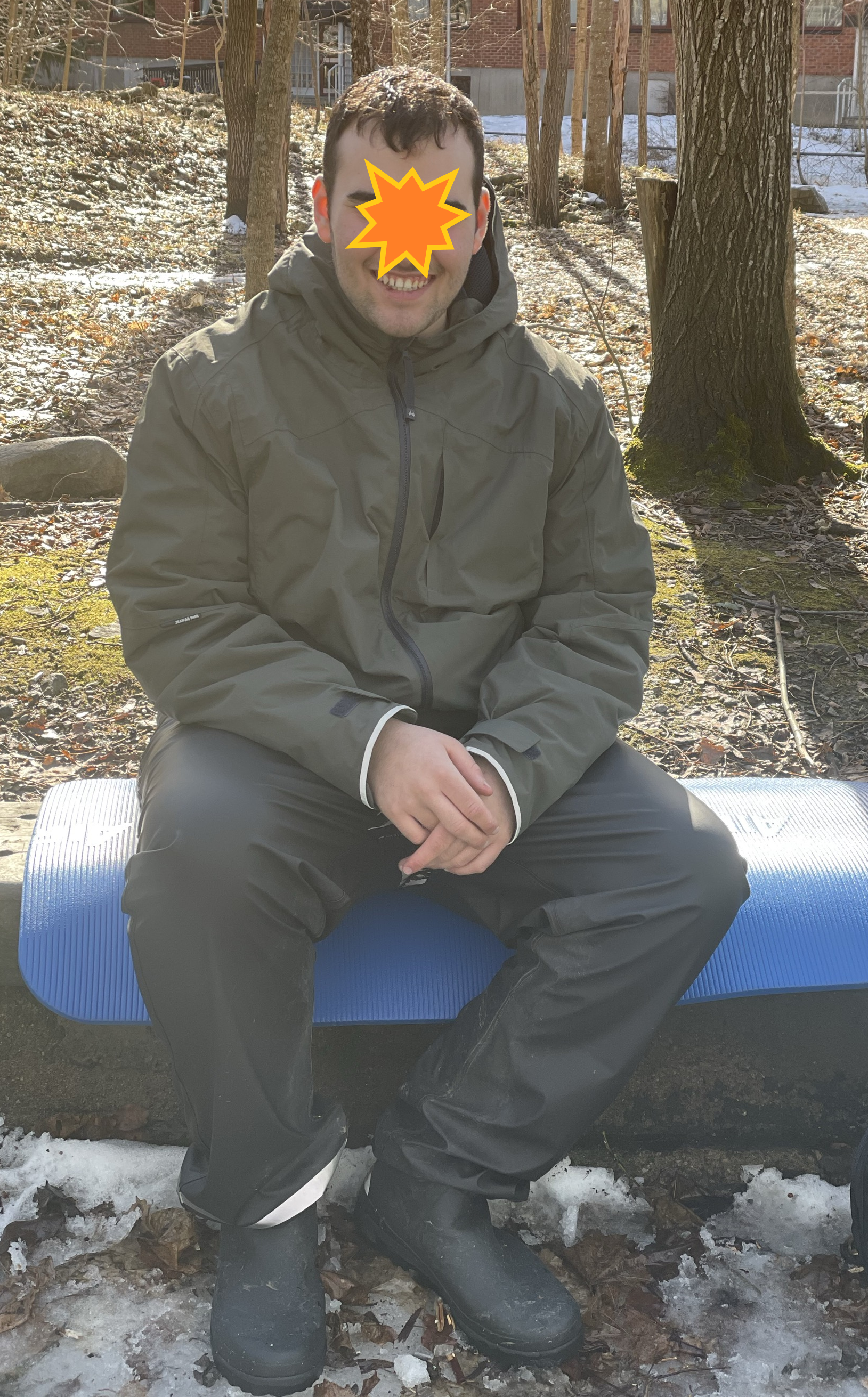 en person som sitter på en benk med maske i ansiktet