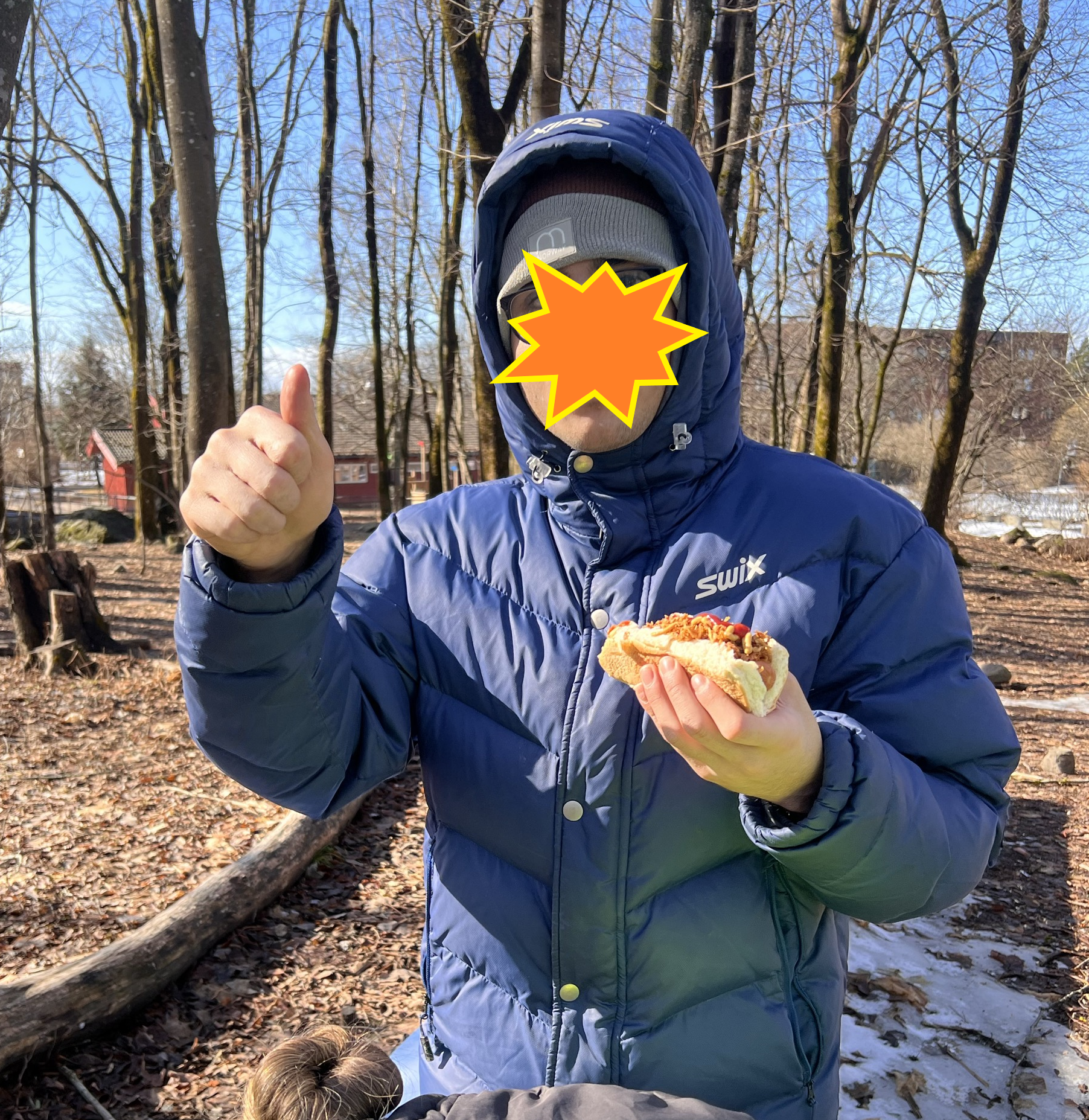 en person som har på seg en maske og holder en pølse