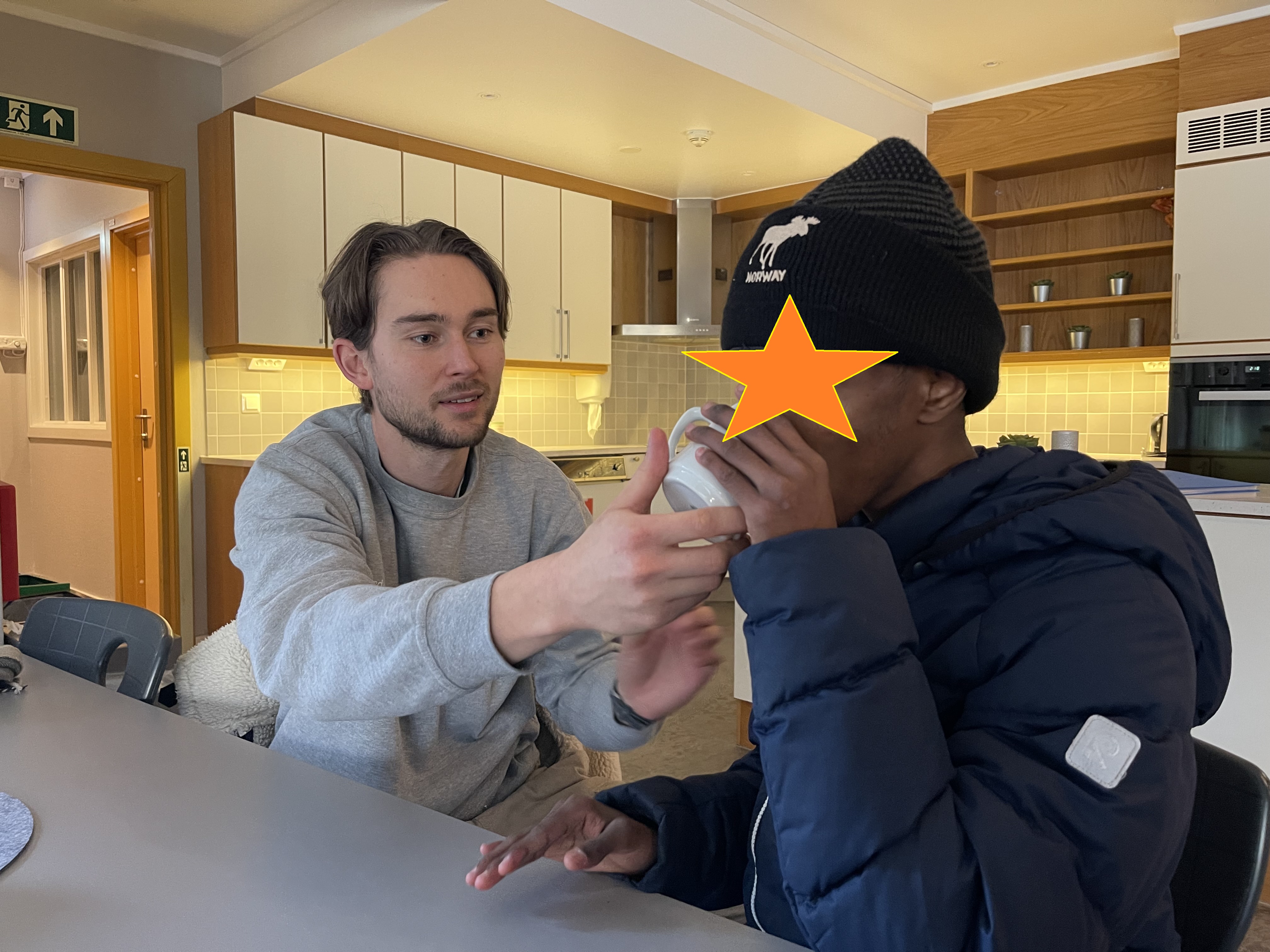 en person som sitter ved et bord med en person i en hatt