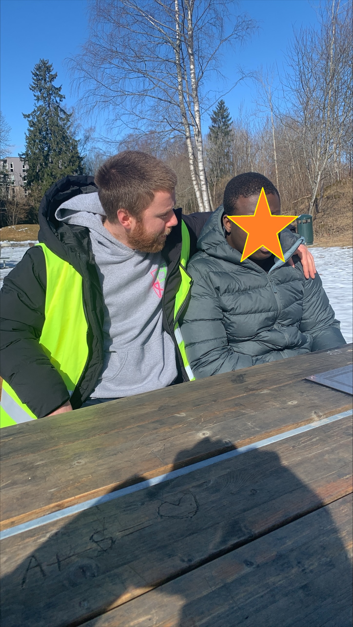 En person som holder en gul og svart gjenstand foran en snødekt bakke