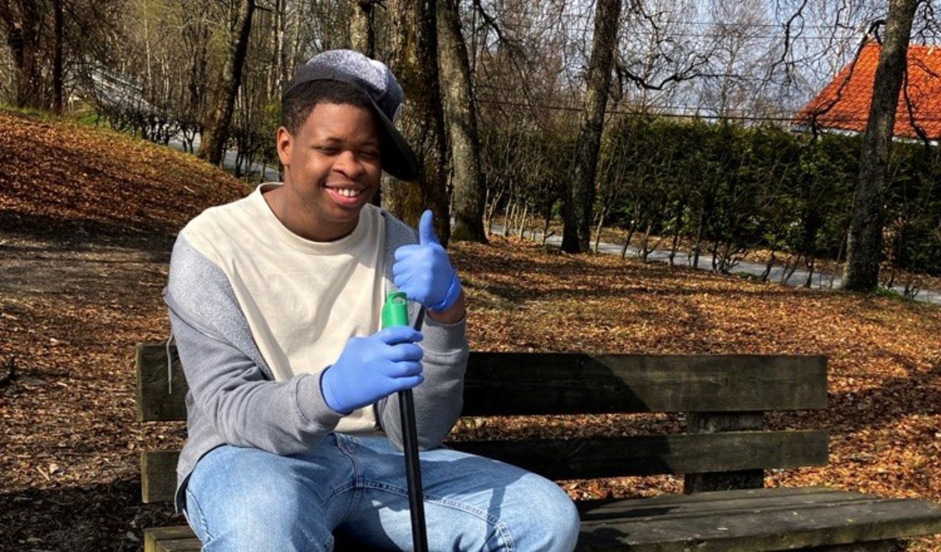 en person som sitter på en benk med en pose søppel